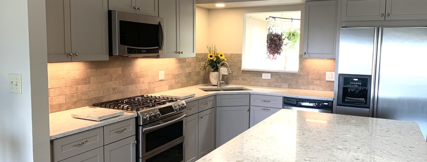 kitchen remodel, wall removal, light gray cabinets, stainless steel appliances, new kitchen island, undermount sink, accent cabinets, shaker cabinets, wood floors, dry stack stone, stone tile backsplash, quartz counter tops